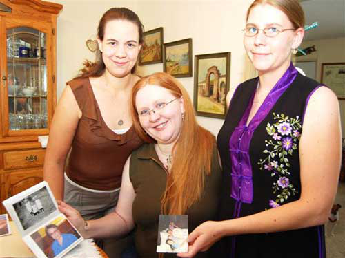 Ida Pennington's three grand-daughters hold up family photos