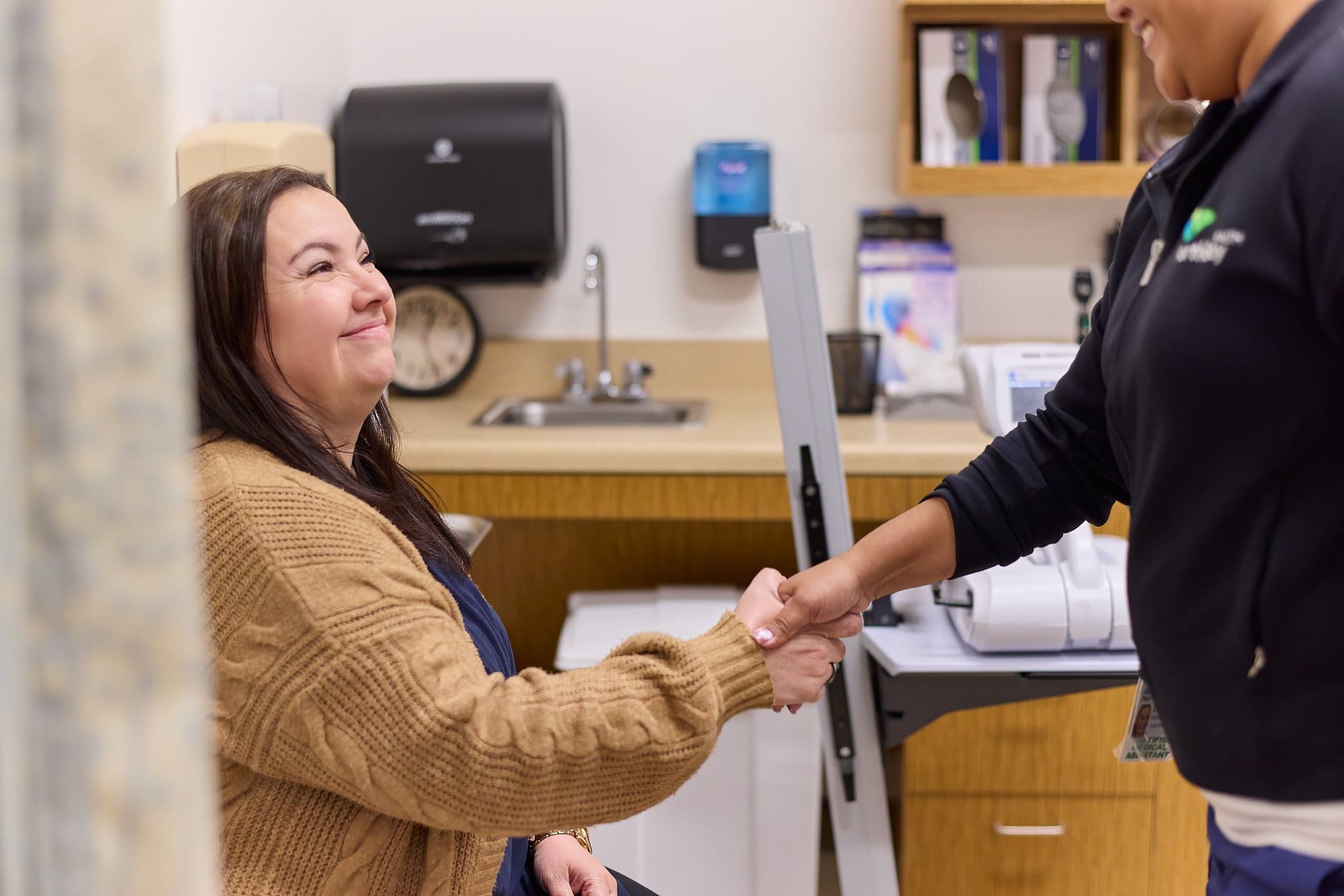 A smiling patient shakes hands with a Northbay Health team member in an exam room.