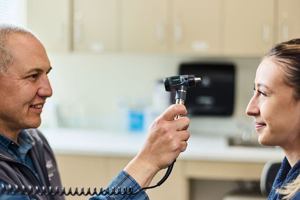 A male doctor uses a lighted instrument while examining a female patient.