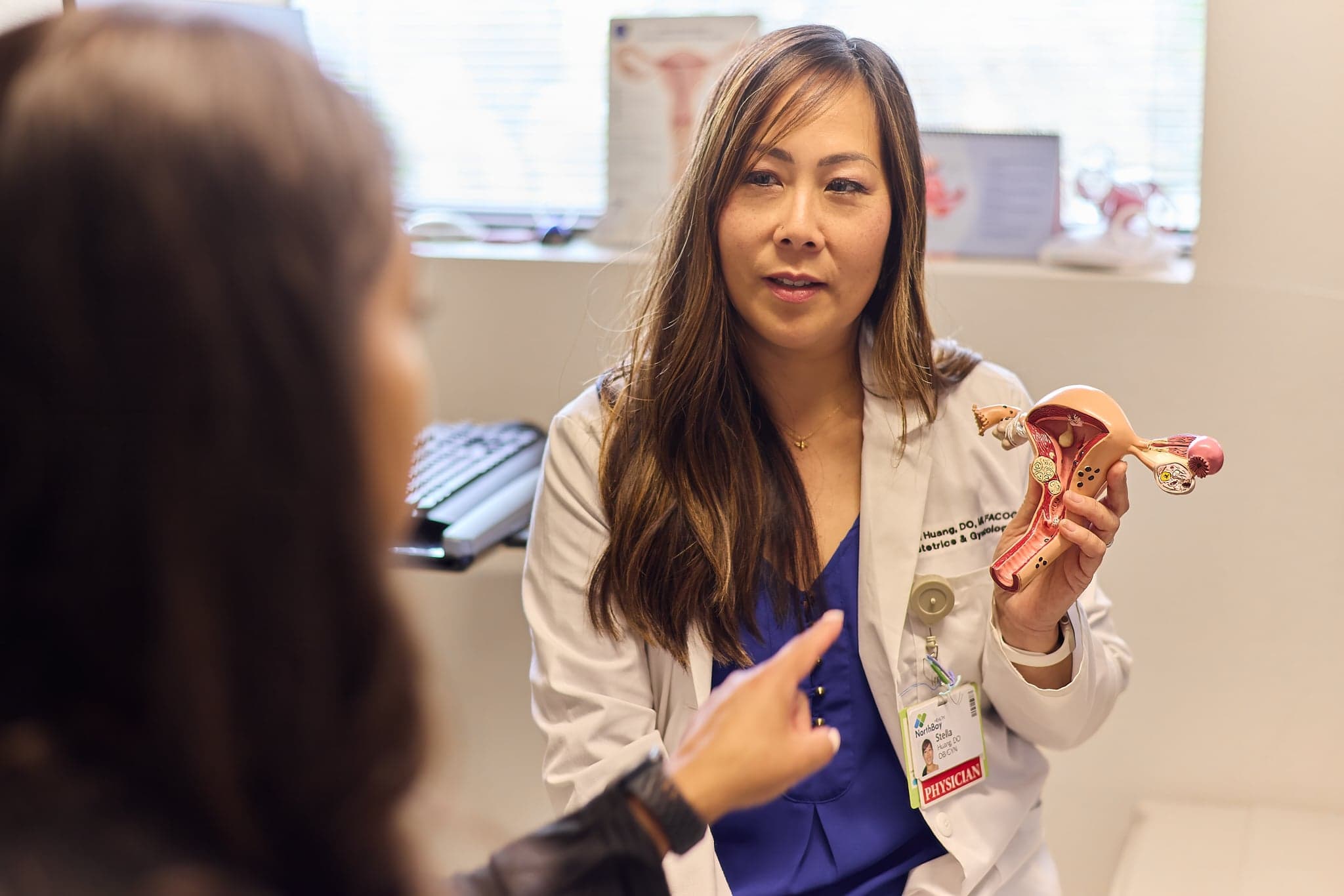 A female ob-gyn shows a medical diagram to a patient.