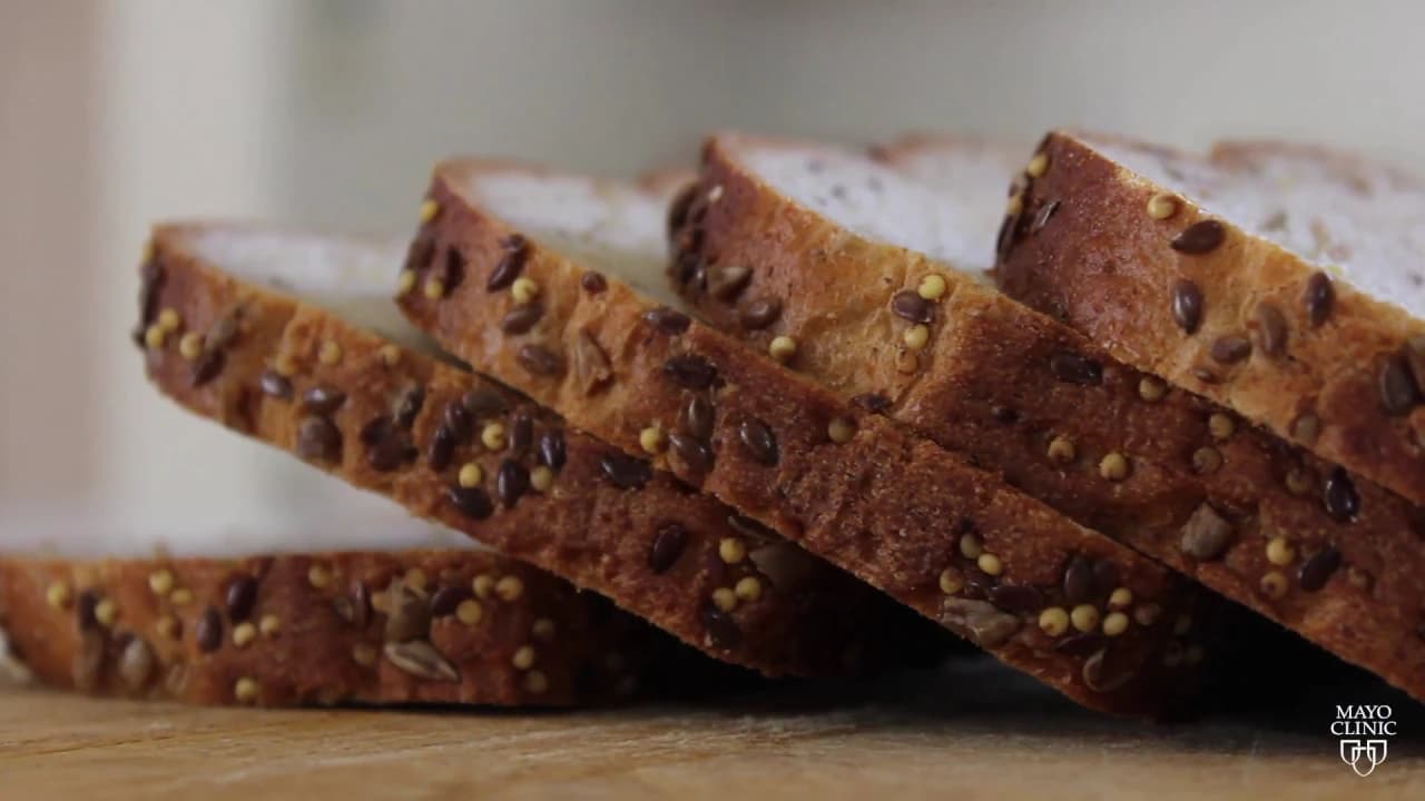 Sliced whole grain bread with seeds arranged on a wooden surface