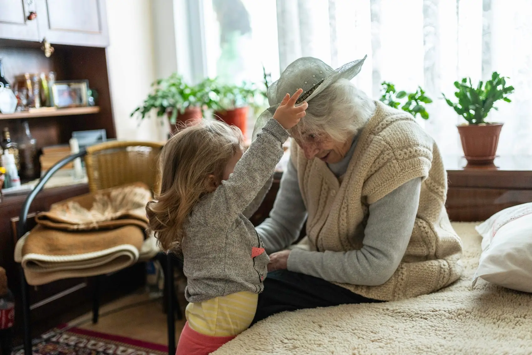 A child adjusts her grandmother's hat