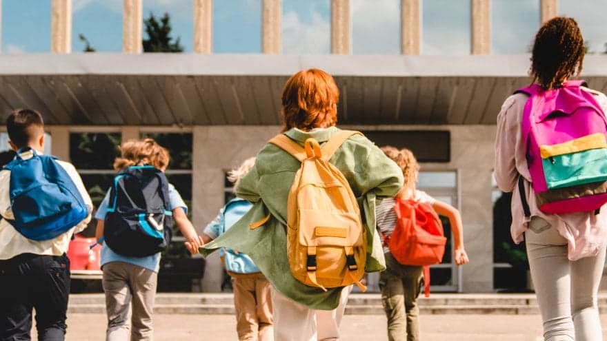 Diverse group of young students walking towards their school.