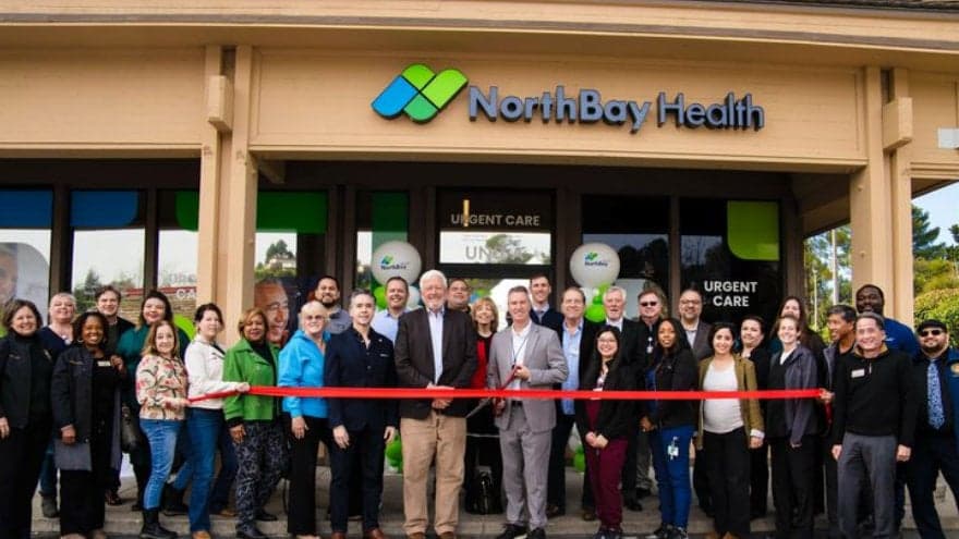 Crowd of Benicia community members and NorthBay Health staff gather behind the red ribbon at the Benicia urgent care clinic grand opening.