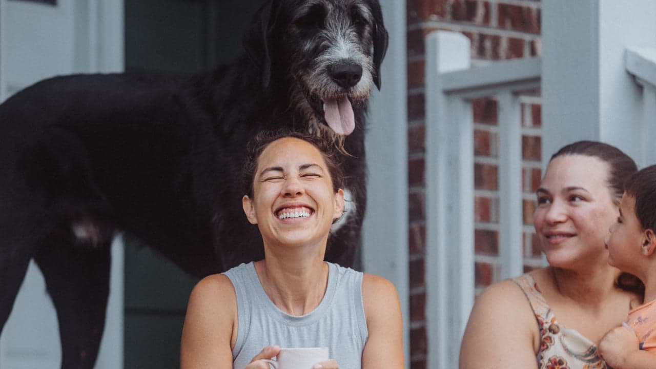 Two women and a dog sit on a porch