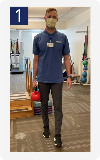 Trainer showing the proper technique for the Suitcase Carry exercise.