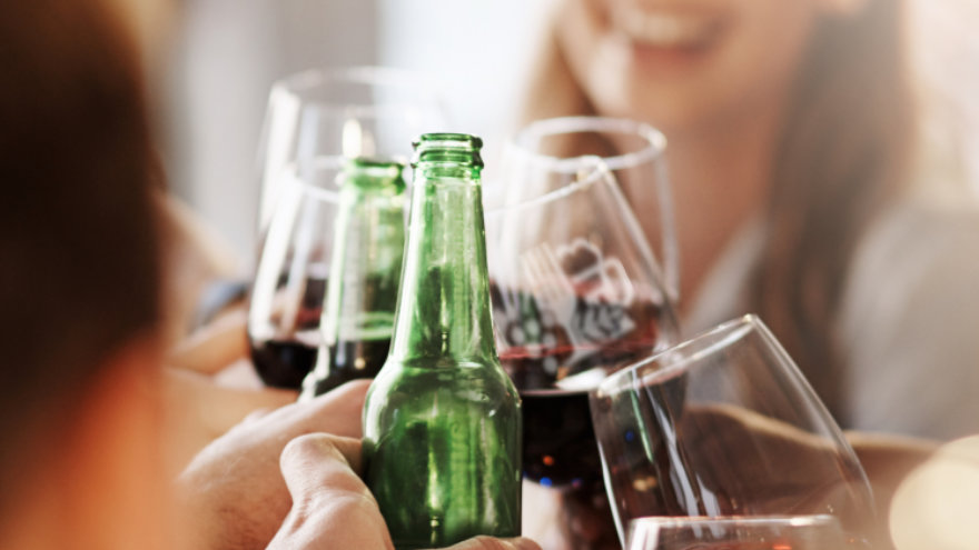 A group of people clinking their wine glasses and beer bottles in a cheers.