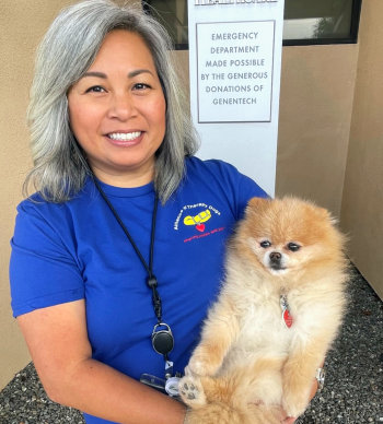 Kat Hsueh, a Certified Alliance of Therapy (CAT) pet owner holding her therapy dog, Mandy.