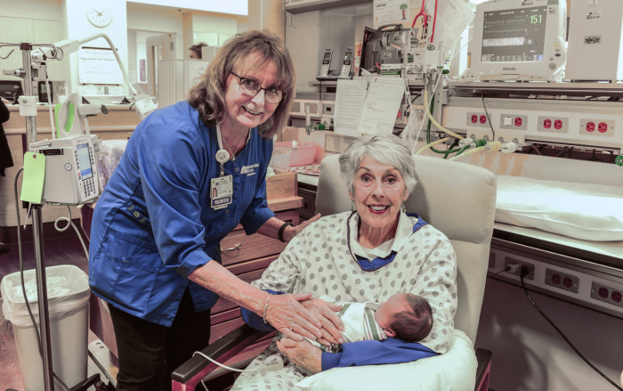 Retired NorthBay Healthcare employee and now volunteer Diane Harris (left), who helped launch the NICU Cuddler program, helps volunteer Gayle Ratliff get settled in for a soothing session with little Wyatt Brenner.