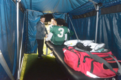 Podiatrist Kevin Miller, D.P.M., attends to a St. Patrick’s High School football player inside the sports medicine tent during a game.