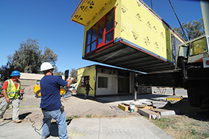 Workers position part of the modular building into place.
