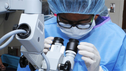 A previous Nurse Camp student peering into a surgical microscope.